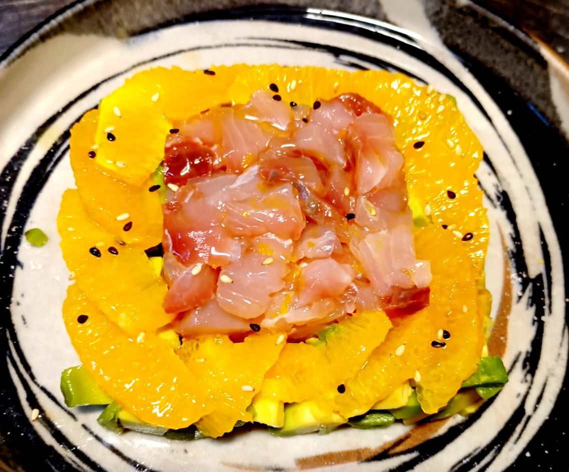 Primo piano di un piatto con fette d'arancia e avocado.