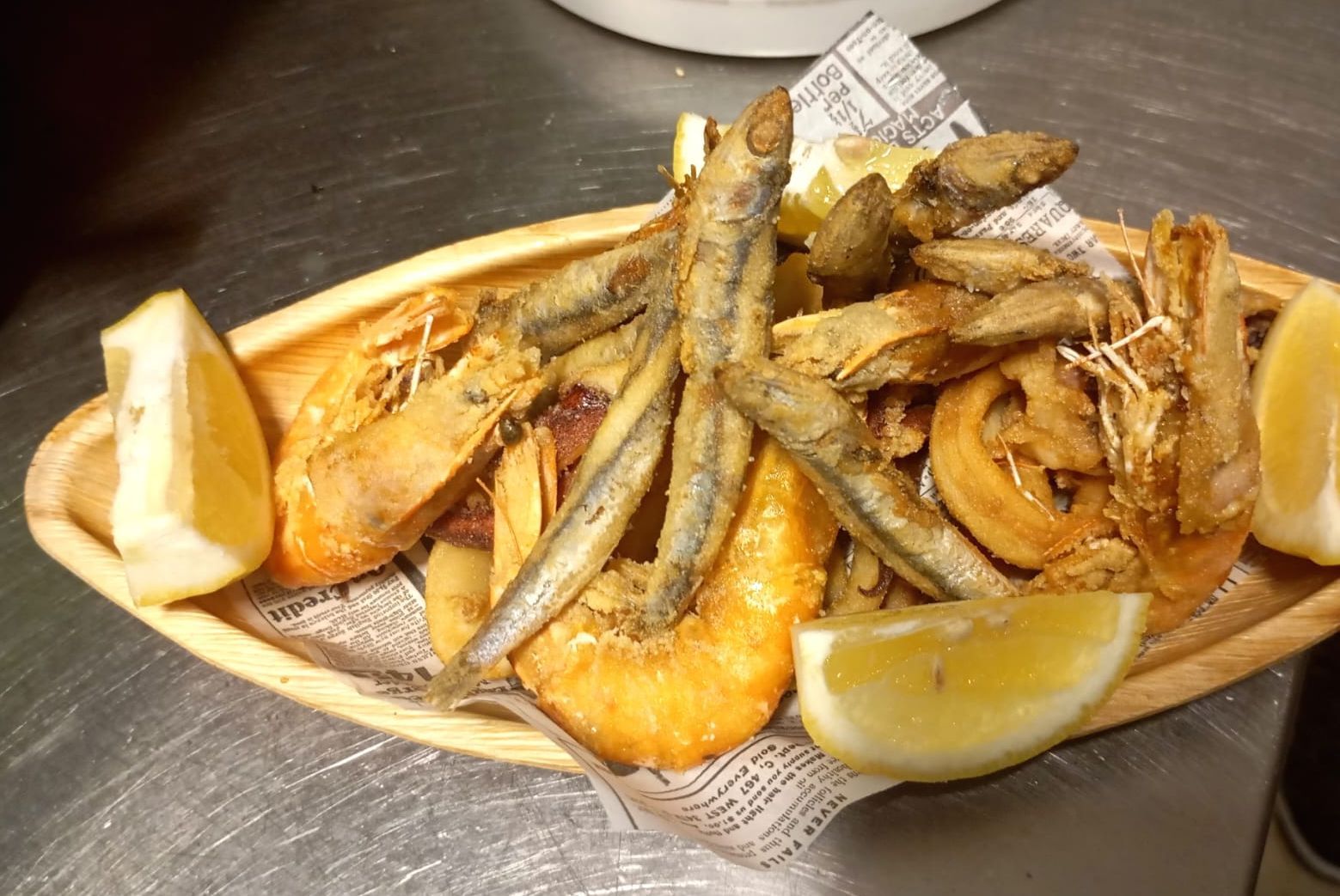 Un piatto di frutti di mare fritti con fette di limone su un tavolo.
