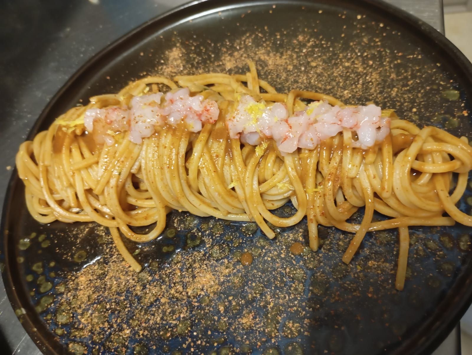 Un piatto nero condito con spaghetti e gamberi