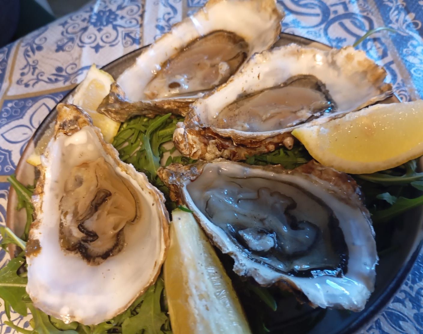 Un piatto di ostriche con fette di limone e verdure su un tavolo.