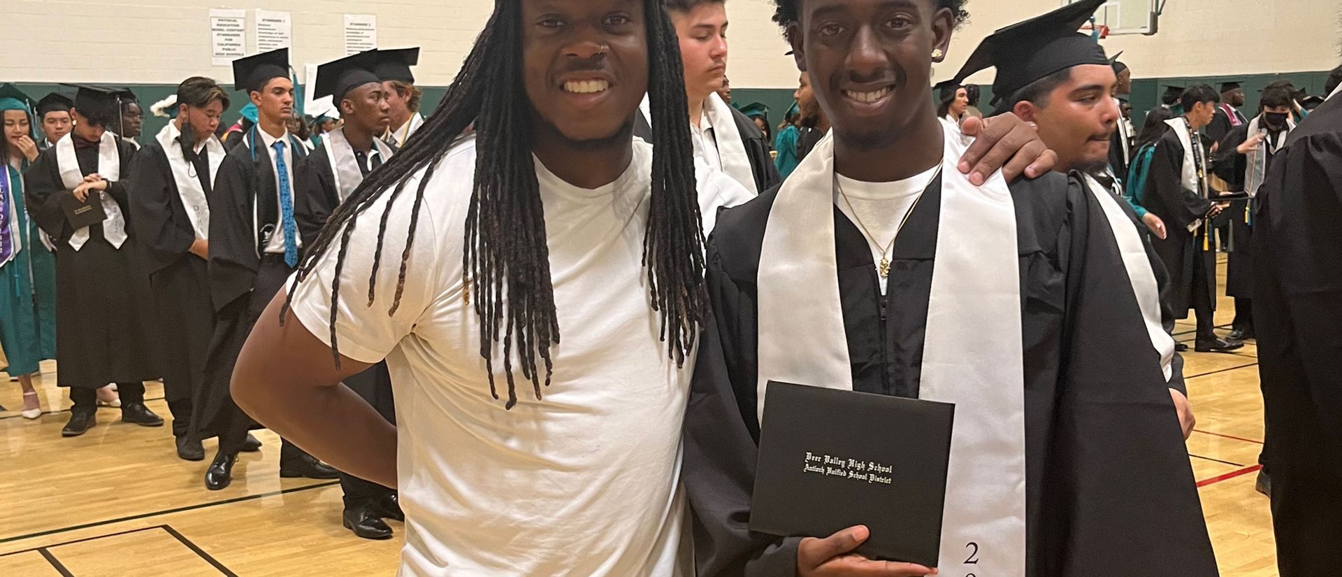 Two men in graduation caps and gowns are posing for a picture.