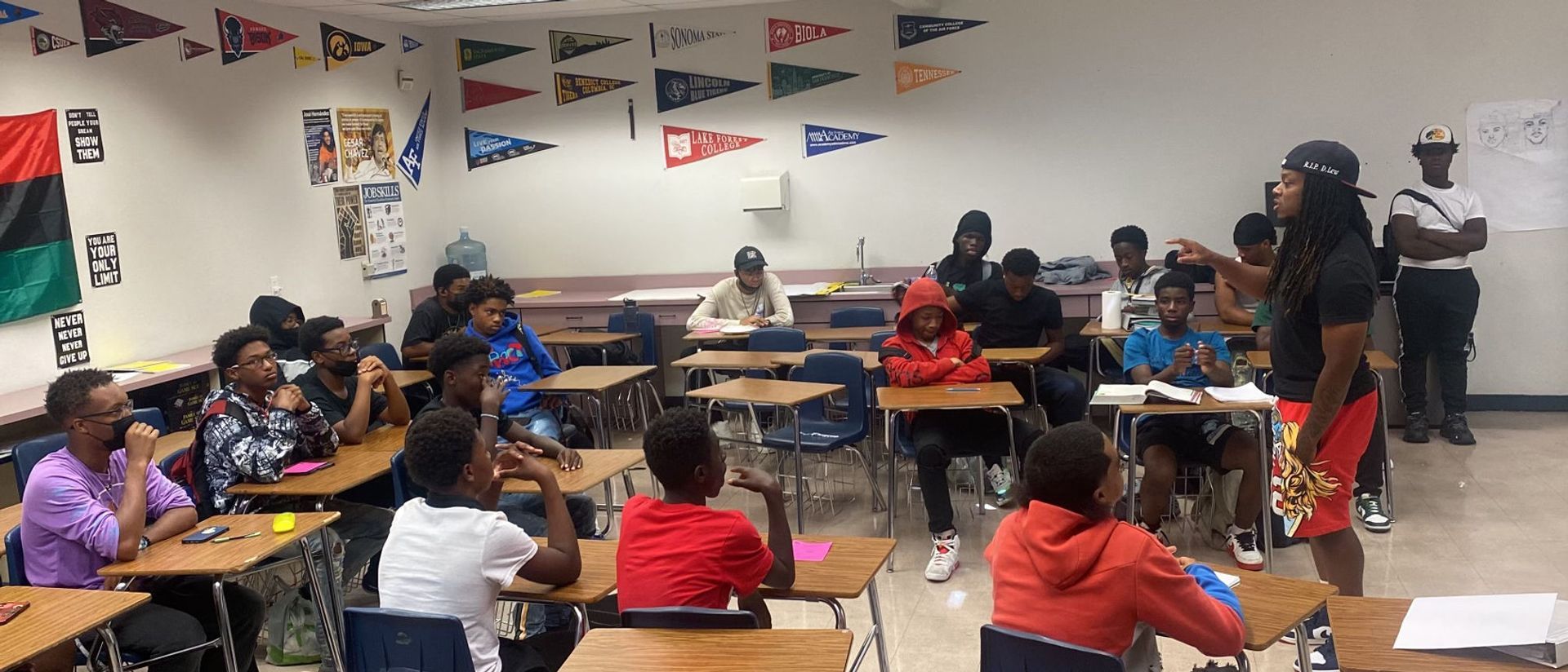 A group of people are sitting at desks in a classroom.