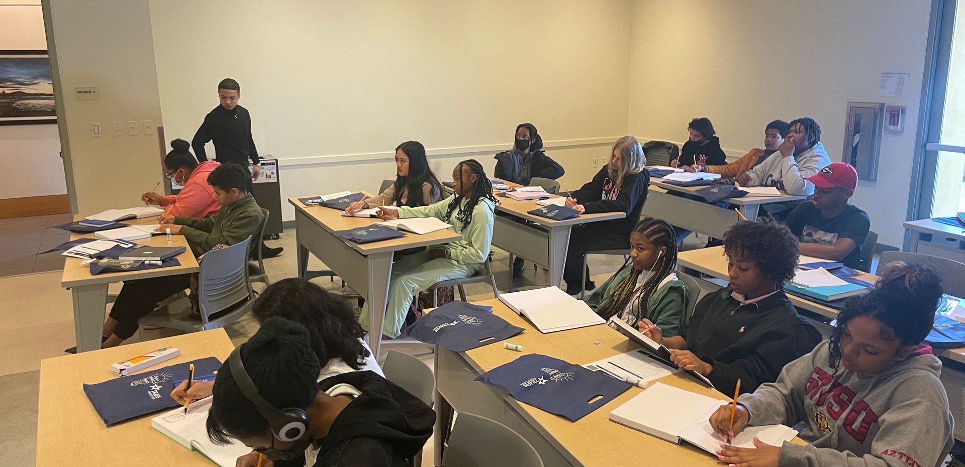 A group of people are sitting at desks in a classroom.