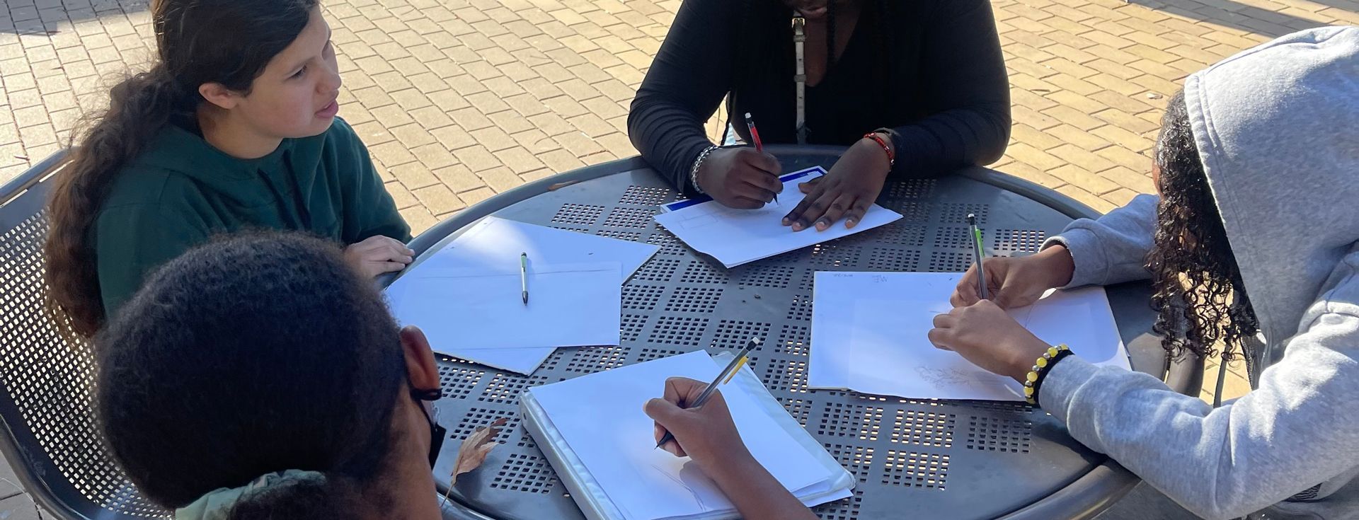 A group of people are sitting around a table writing on papers.