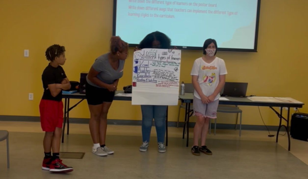 A group of people are standing around a table holding a sign that says ' i love you ' on it.