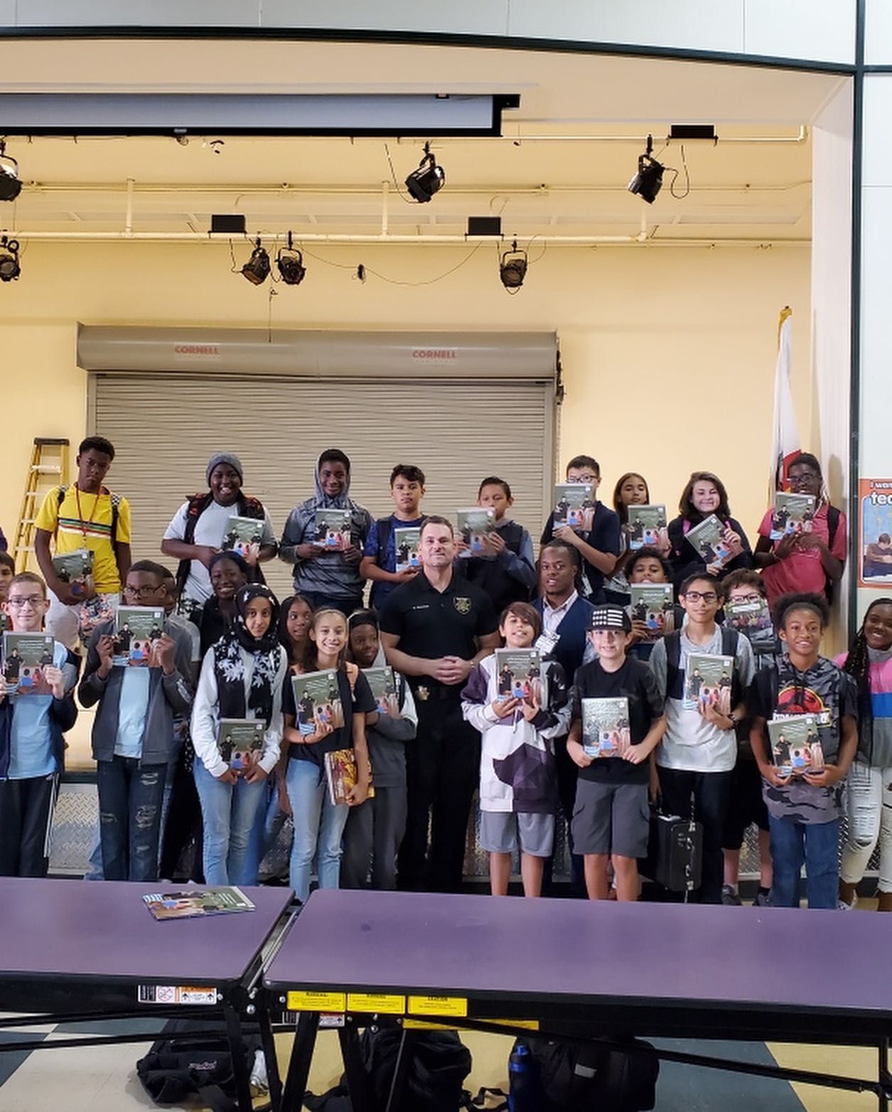 A group of children are standing around a table holding books.