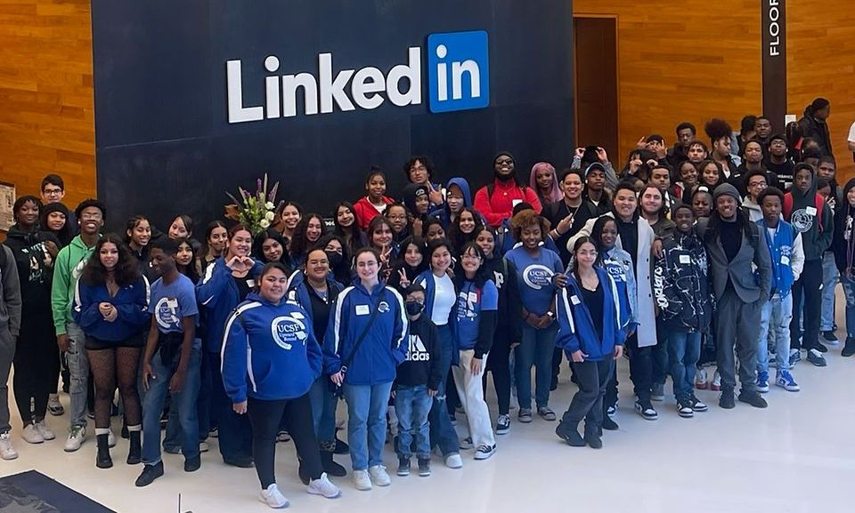 A large group of people are posing in front of a sign that says linked in