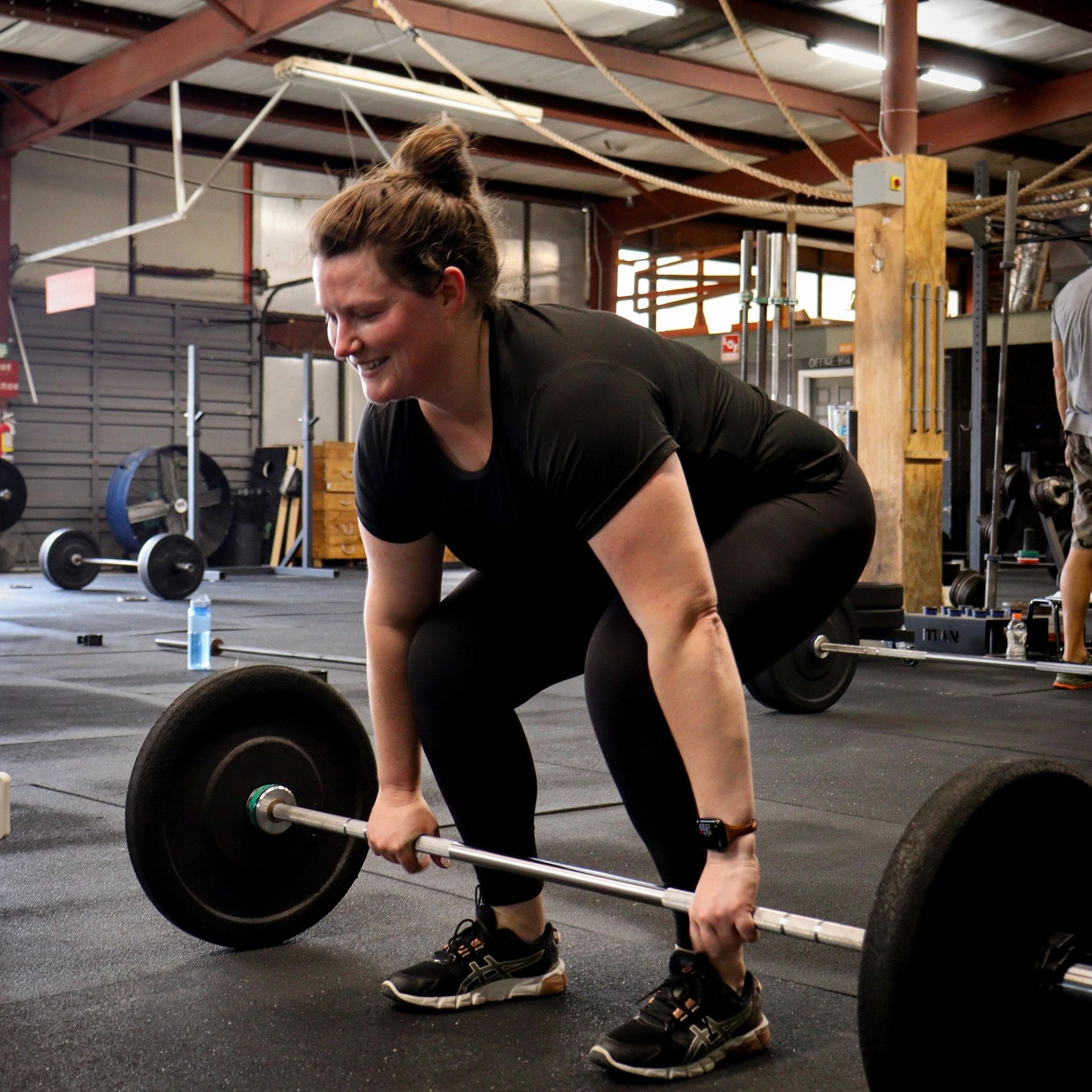 A woman is lifting a barbell in a gym