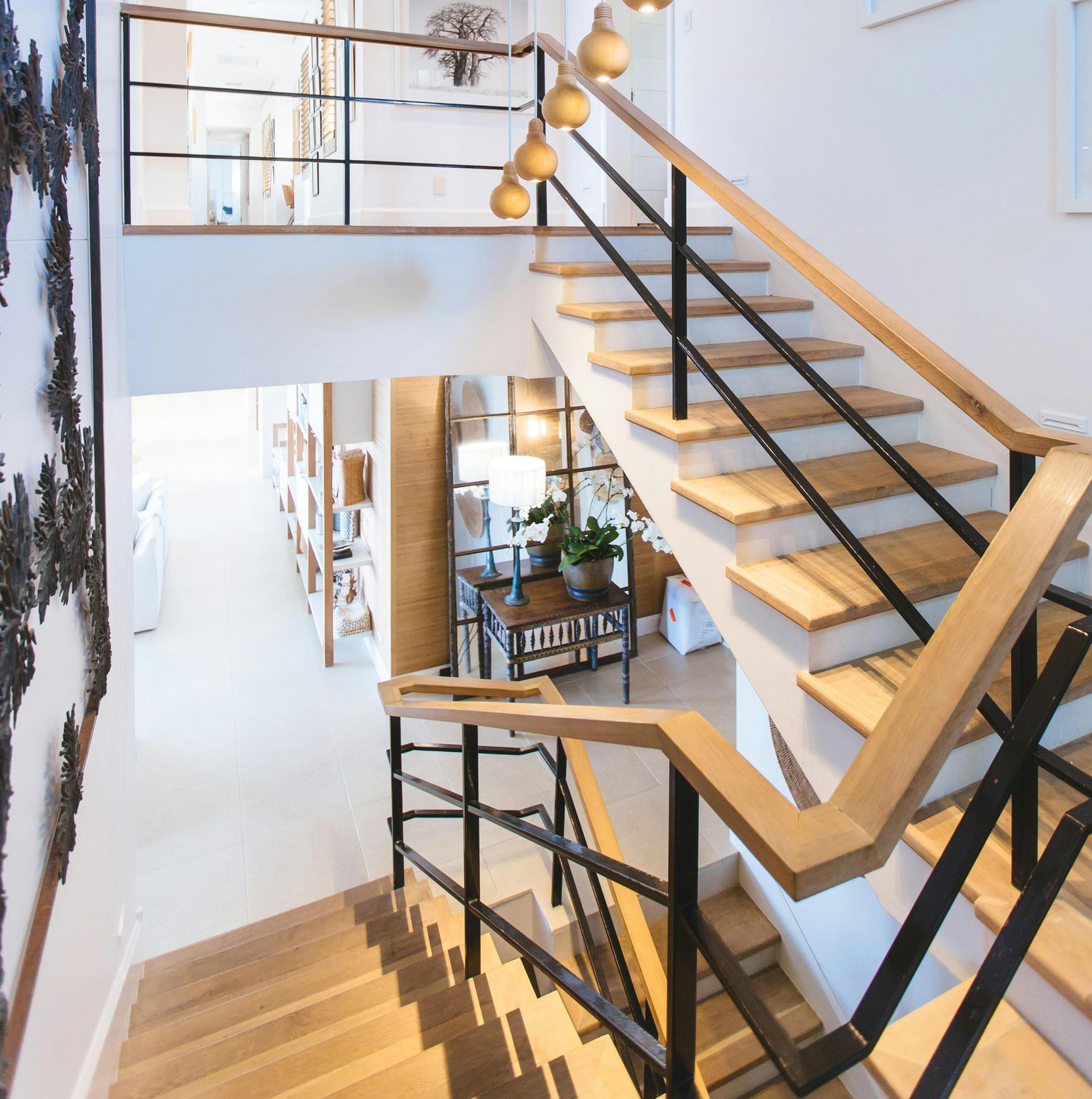 Modern indoor staircase with wood steps and black railings in a Town ānā Country home.