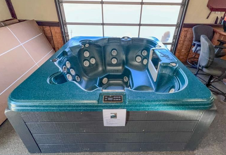 Hot tub with light brown wood paneling sits inside a garage with glass door.