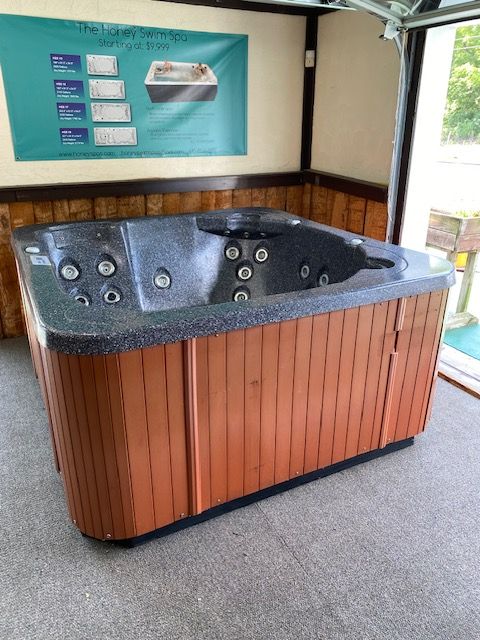 Hot tub with a wooden cabinet and black interior, inside a room.
