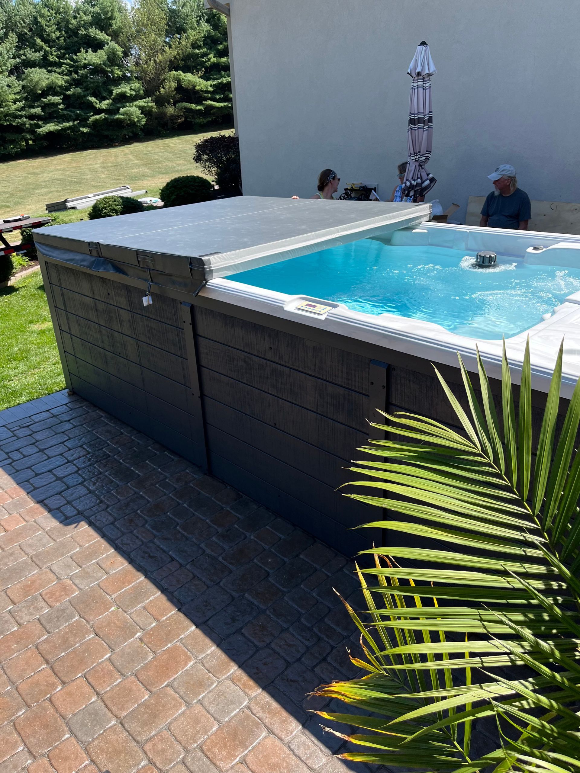 Backyard with a grey hot tub under a pergola, a concrete patio, and seating.