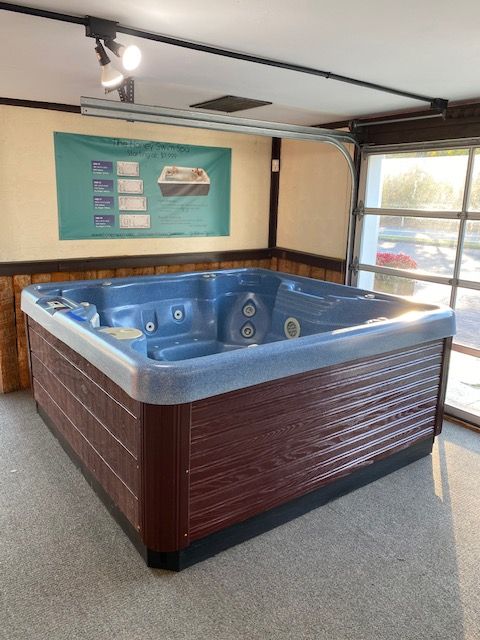 A large, rectangular hot tub with blue interior and brown exterior, indoors with a sunny window.