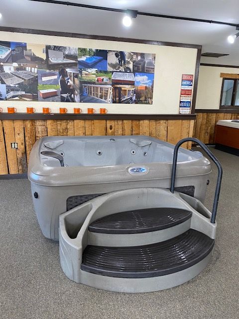 Hot tub with gray steps and handrail in a showroom.