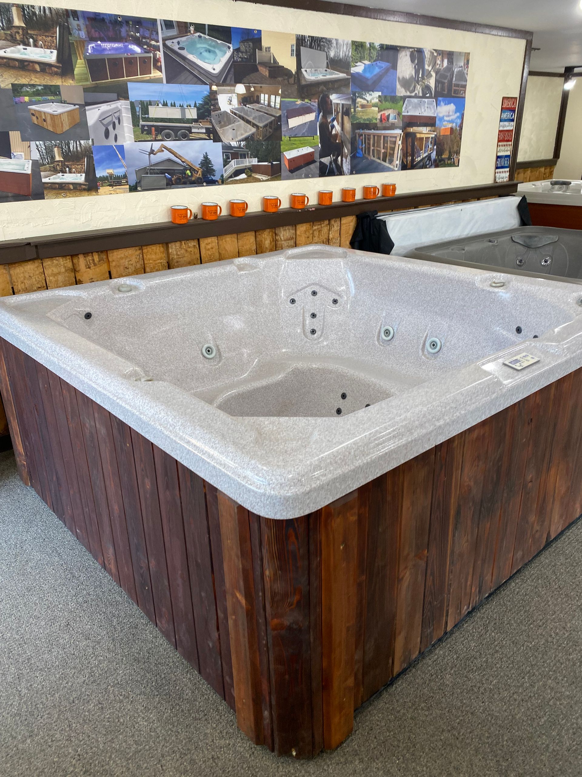 Hot tub with wood paneling in a showroom with pictures on the wall.