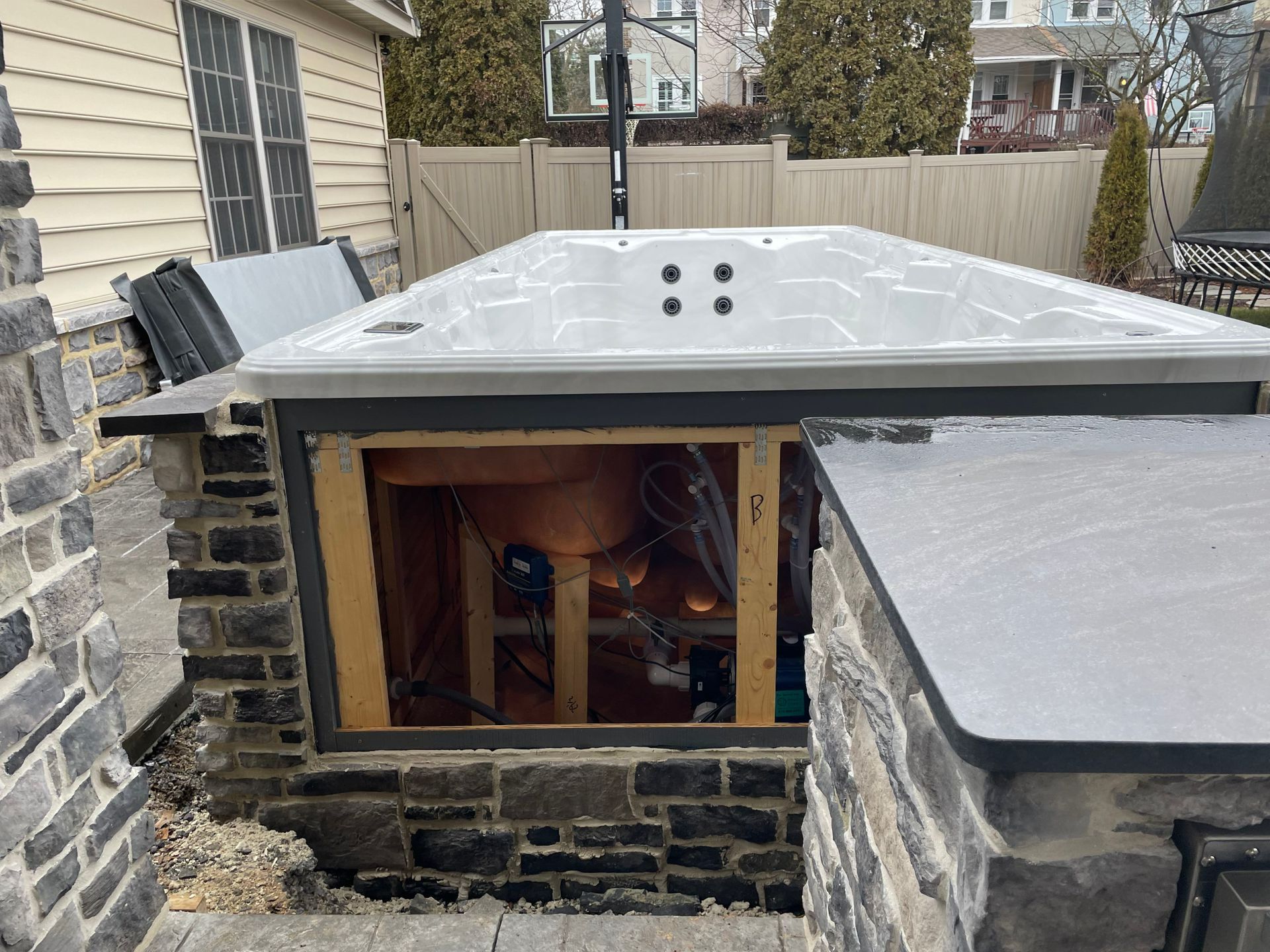 A hot tub installed in a stone surround, with the equipment compartment exposed.