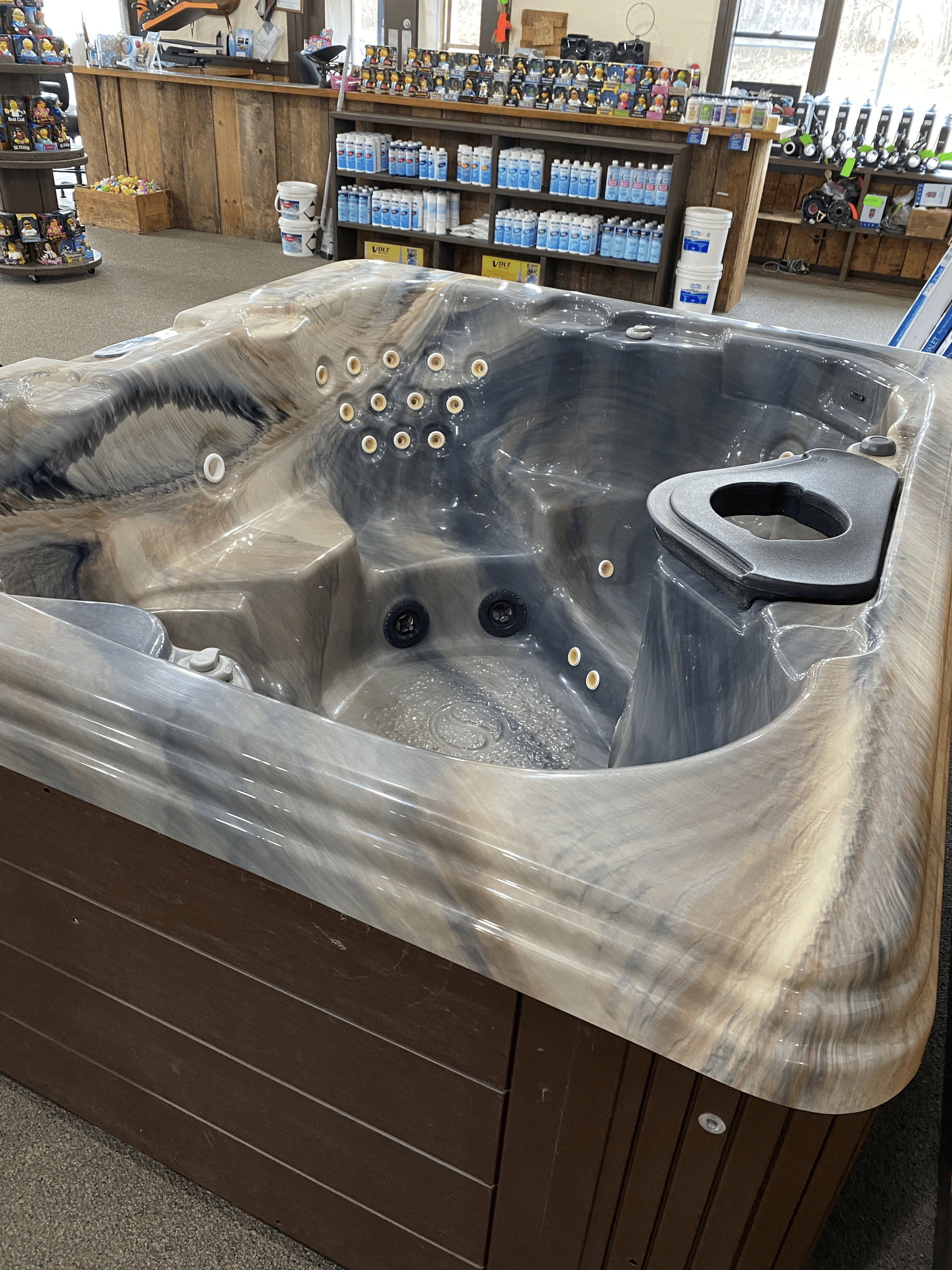 A small, gray hot tub with a black cover sits indoors.