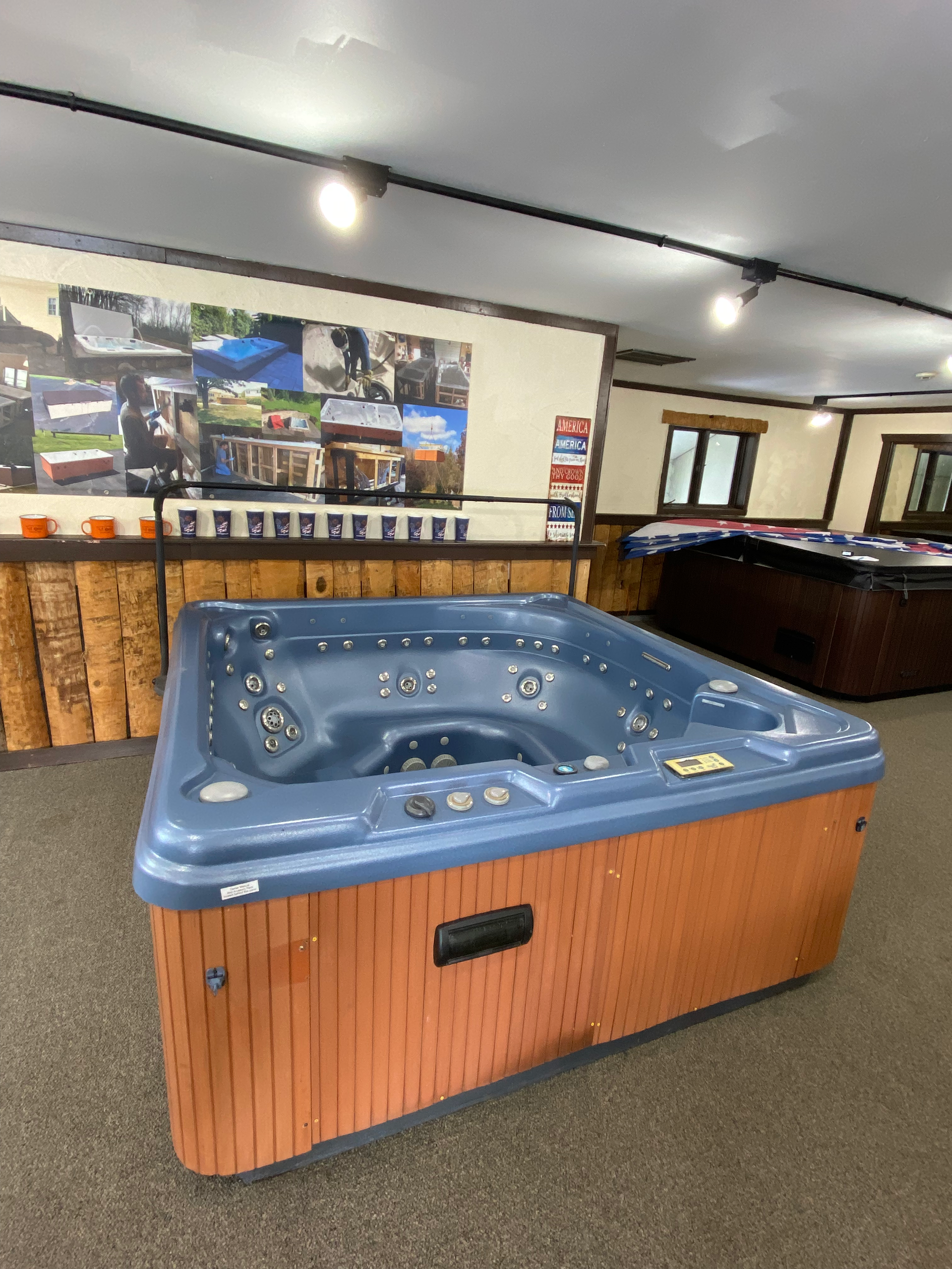 Hot tub in a garage, with a brown wood-like exterior and white interior, ready for installation.