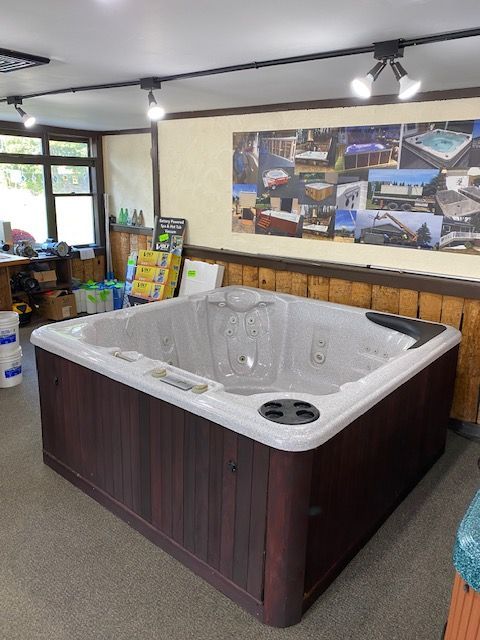 Hot tub on display in a showroom with dark wood siding, white trim, and brown interior.
