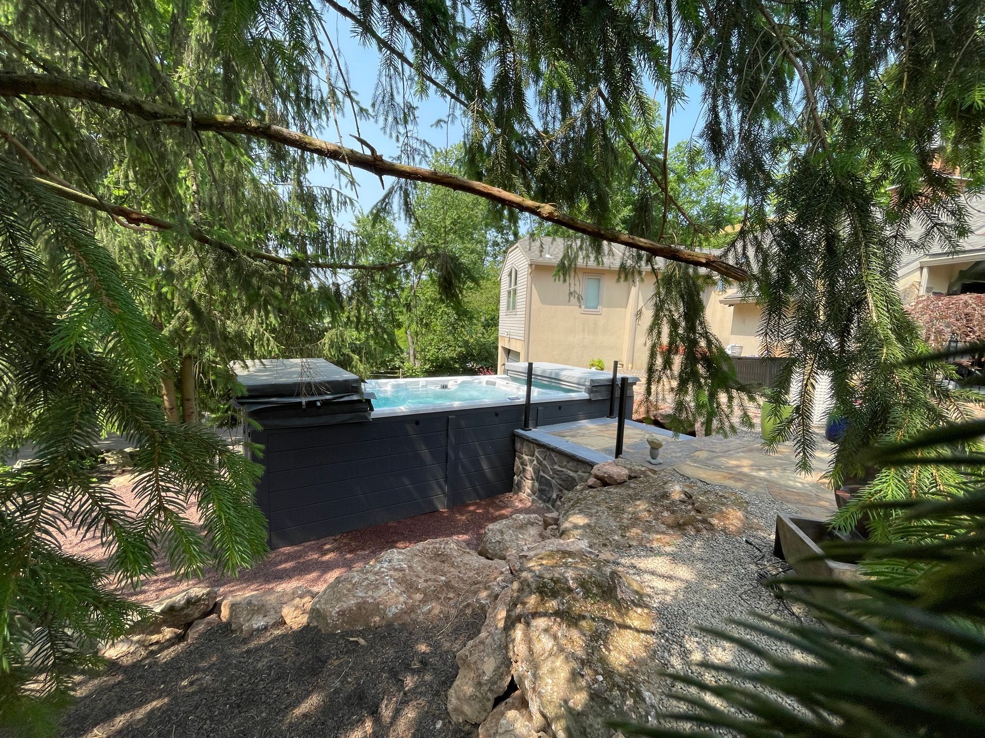 A rectangular pool, next to a building, viewed from behind trees.