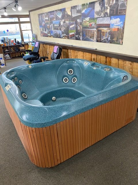 Blue hot tub with wood paneling, in a showroom setting.