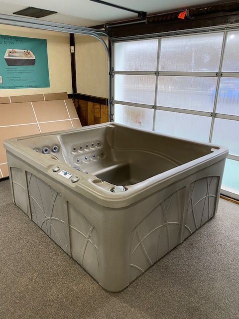 Tan hot tub in a garage with a frosted window.