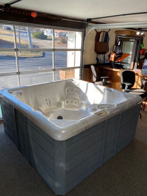 A large, gray hot tub inside a garage with a glass door.