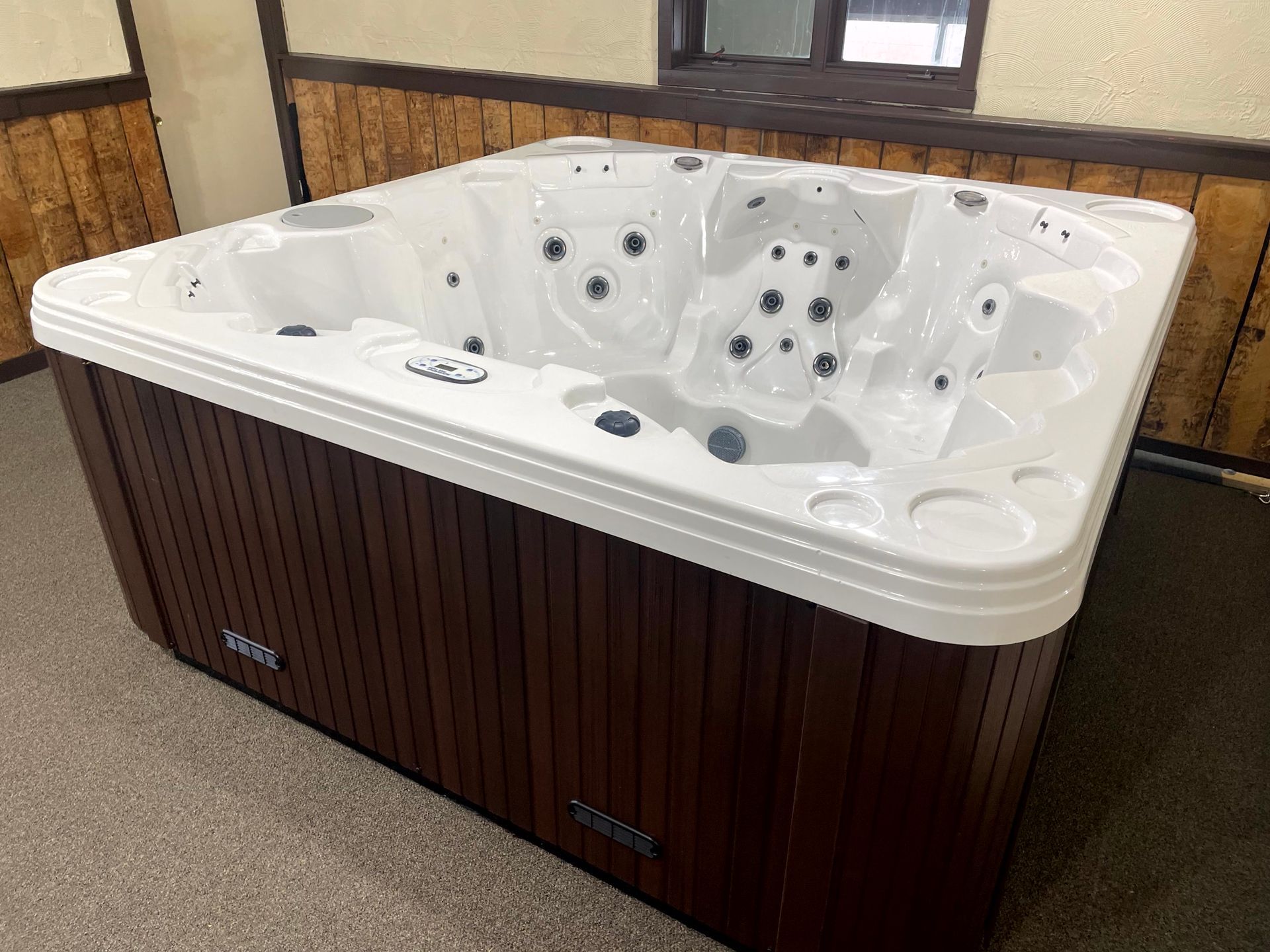 A small, gray hot tub with a black cover sits indoors.