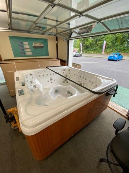 Hot tub in a garage, with a brown wood-like exterior and white interior, ready for installation.