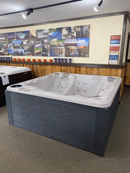 Square gray hot tub with white interior in a showroom.