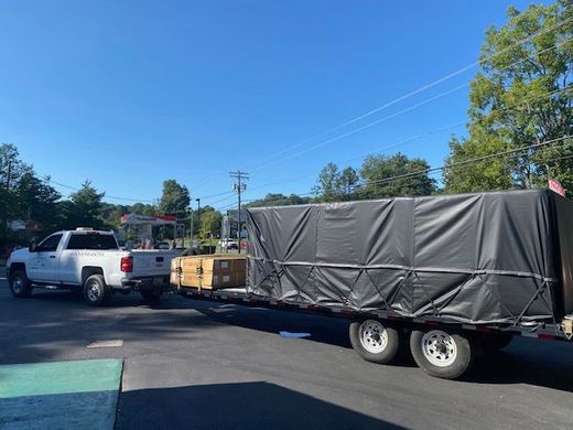 A white truck is towing a trailer with boxes on it.