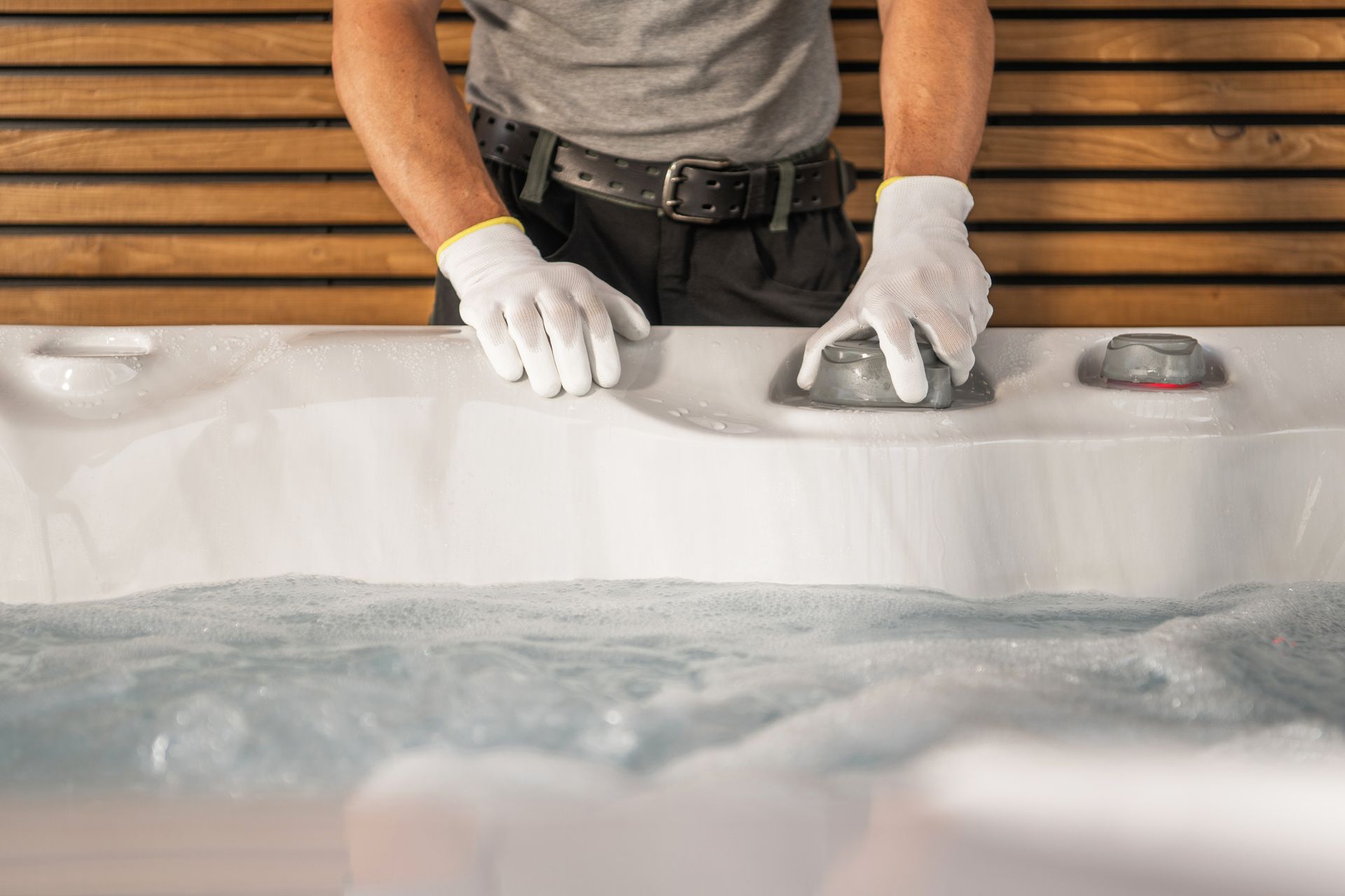Technician adjusting hot tub controls during spa maintenance service.