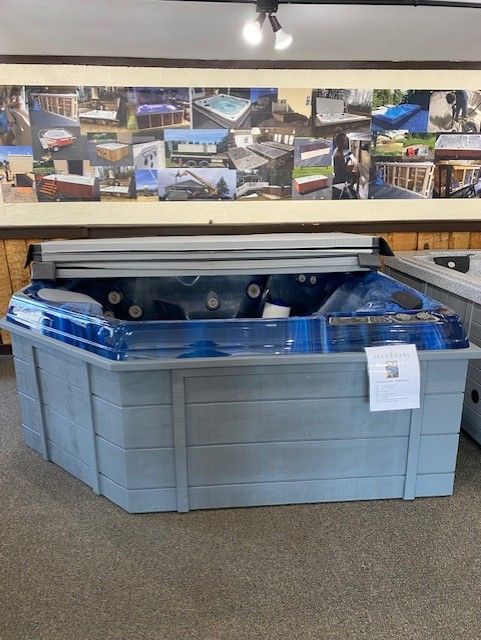 Blue hot tub with grey siding, interior store setting.