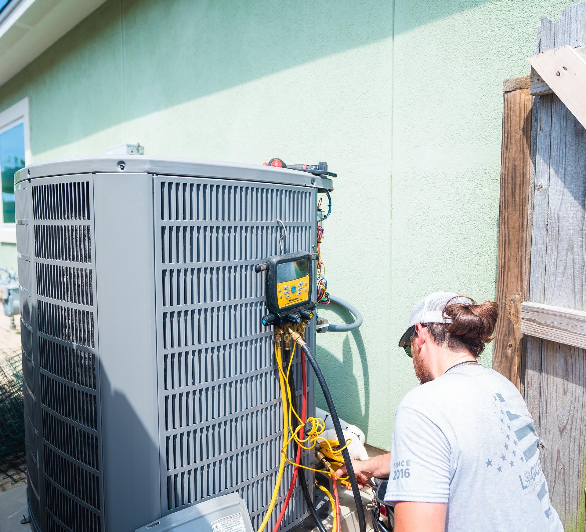 Logicool HVAC technician performing spring air conditioning maintenance on outdoor unit.