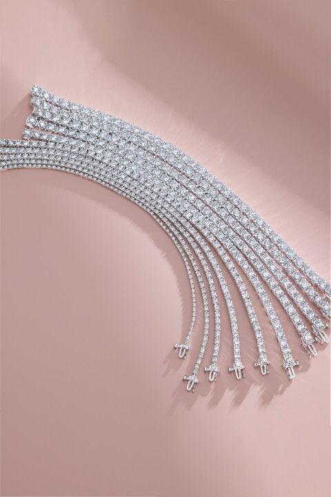 A row of diamond bracelets are lined up on a pink surface.