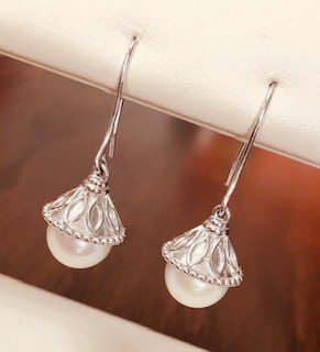 A pair of pearl earrings are sitting on a white surface.