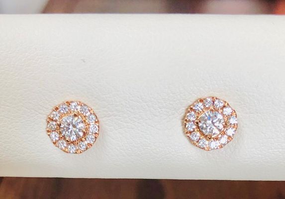 A pair of diamond stud earrings are sitting on a white surface.