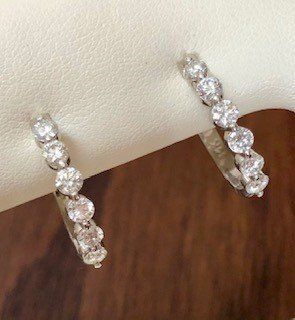 A pair of diamond hoop earrings are sitting on a wooden table.