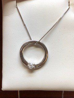 A close up of a necklace with a diamond in the center.