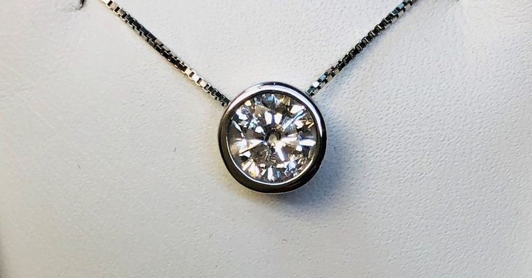 A close up of a necklace with a diamond pendant