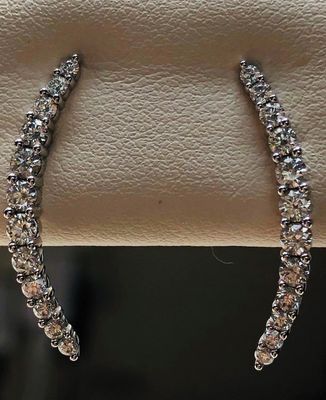 A pair of diamond hoop earrings are sitting on a leather surface