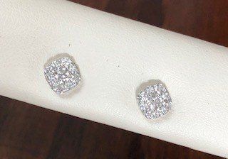 A pair of diamond stud earrings are sitting on a napkin on a table.