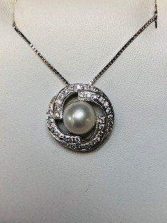 A necklace with a pearl and diamonds on a chain.