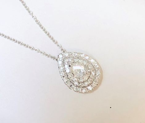 A necklace with a pear shaped diamond pendant on a chain.