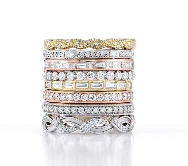 A stack of wedding rings are stacked on top of each other on a white surface.