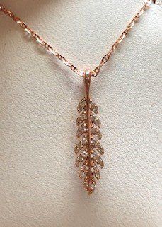 A close up of a necklace with a leaf shaped pendant on a chain.