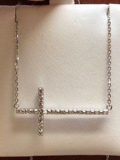 A necklace with a cross on it is on a white surface.