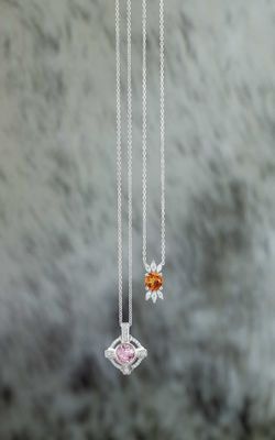 Three necklaces are hanging from a chain on a marble surface.