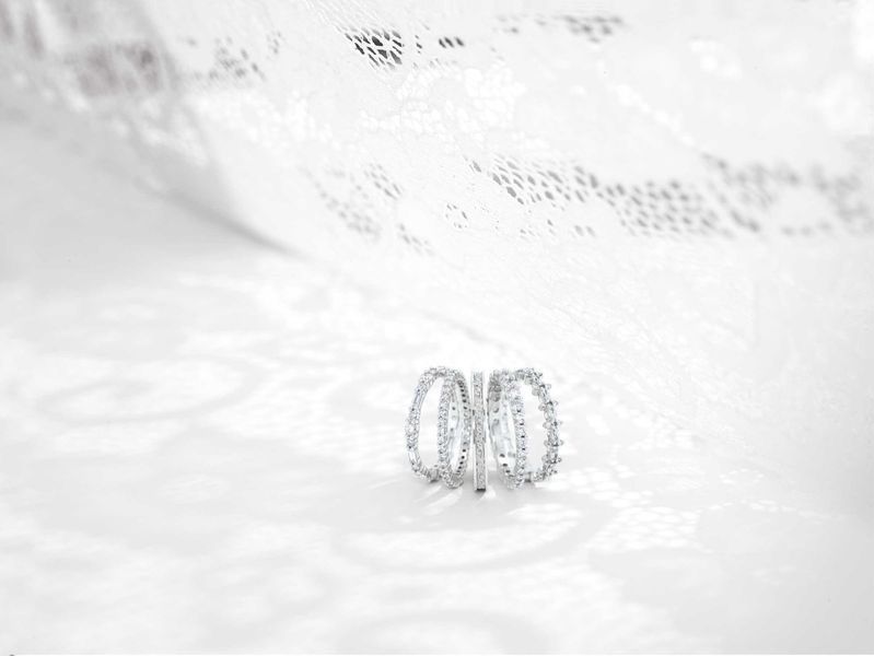 A close up of a diamond ring on a white surface.