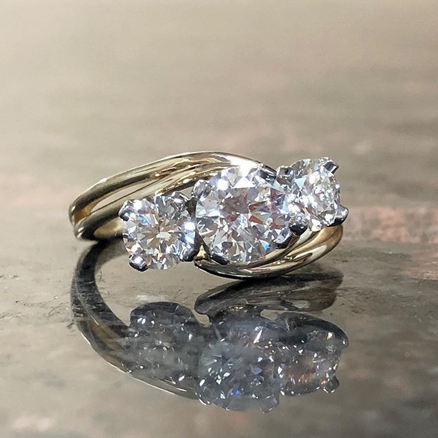 A gold ring with three diamonds is sitting on a table.